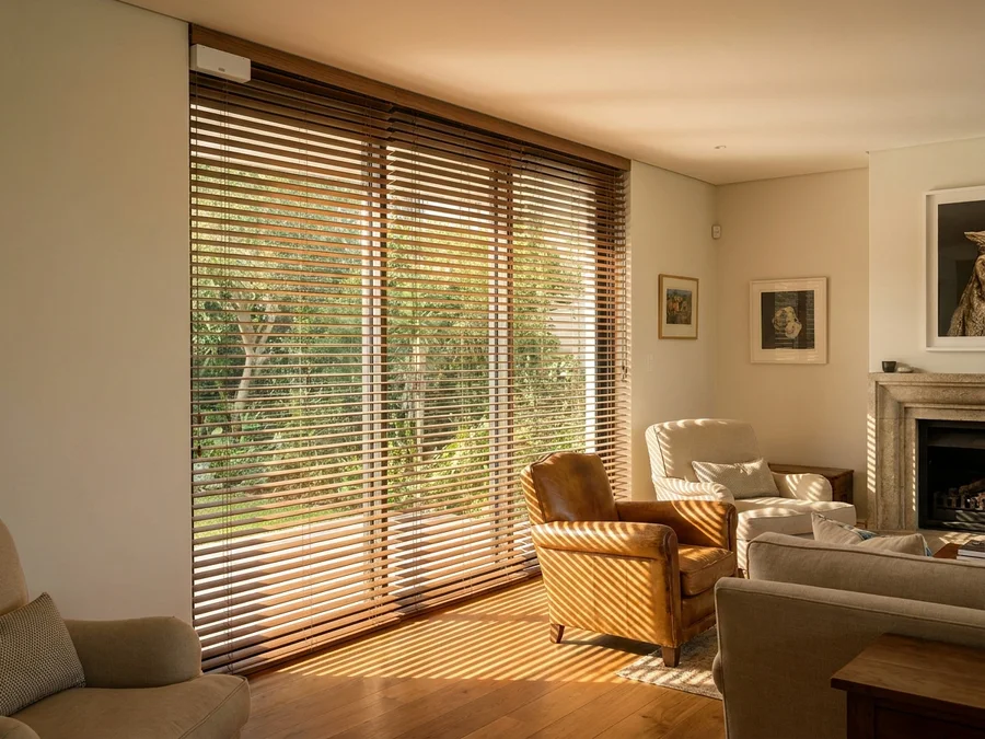 Motorised timber venetian blind tilted to a set angle over a double-height Bishopscourt window, motor housing at the headrail